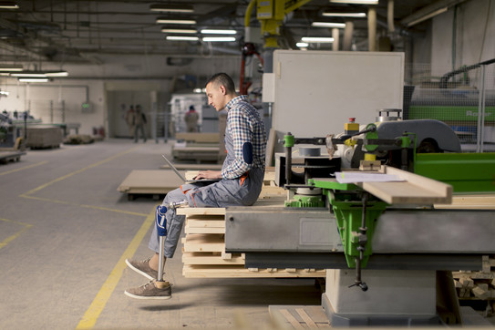 Person mit Beinprothese in einer Maschinenhalle
