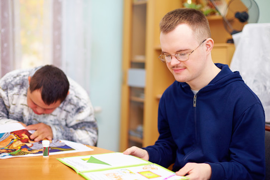 Person in Rehabilitationseinrichtung sitzt vor aufgeschlagenem Heft