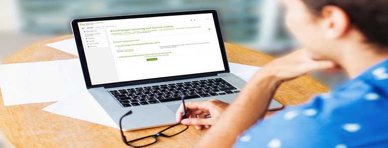 Studierende sitzt am Arbeitsplatz und schaut auf den Laptop.